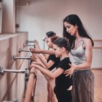 Expirienced ballet teacher is showing to young girls how to do important exercises